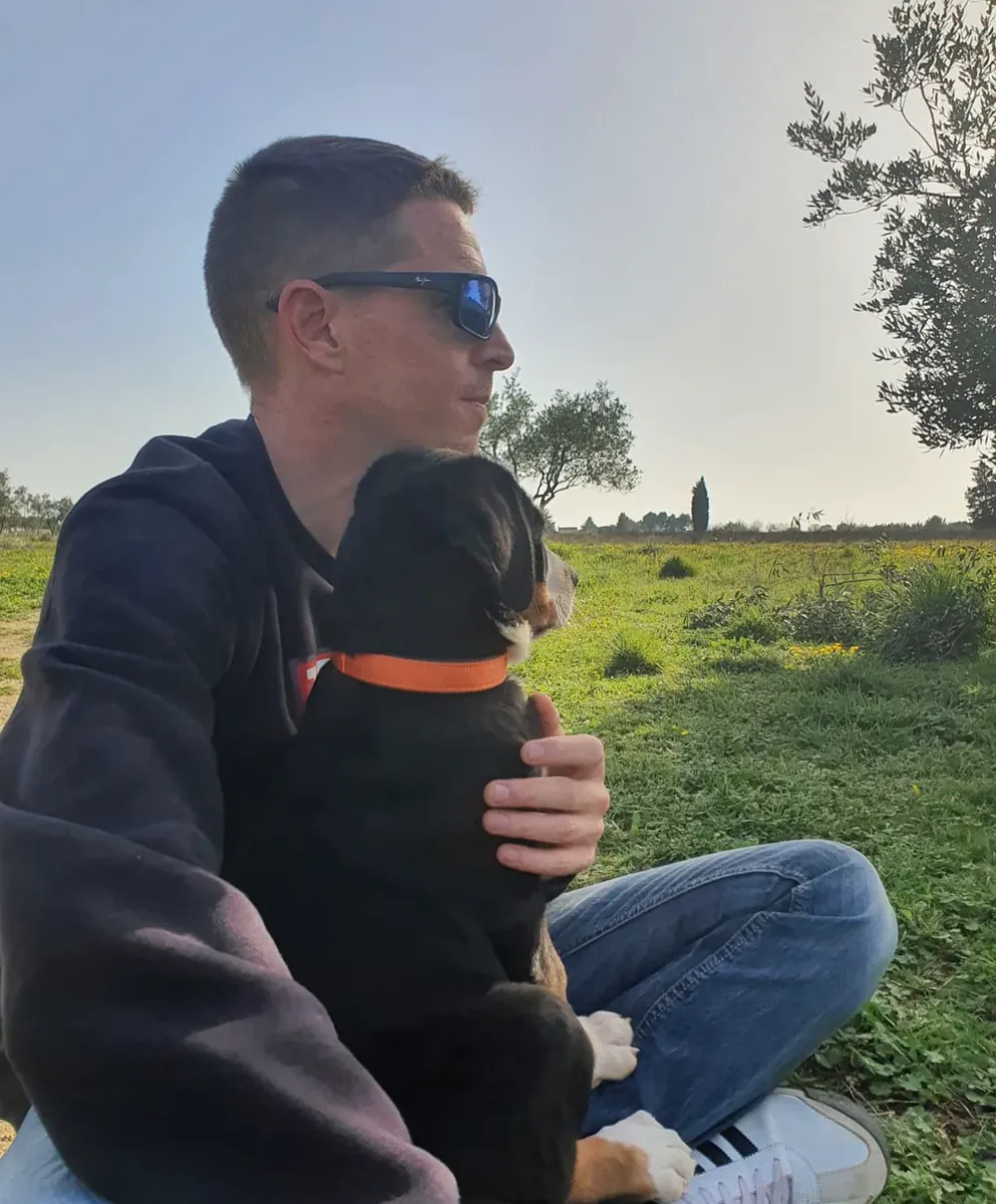 Une personne enlace son chien assise dans l’herbe